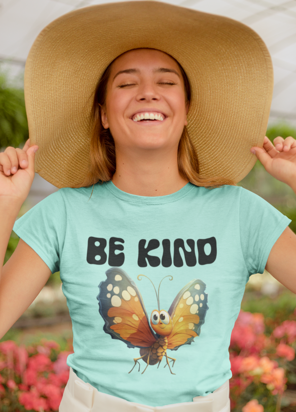 Woman wearing an Iced Teal tee with a sun colorful butterfly and the words BE KIND on the front.  Tee is available in small to 2xl. 